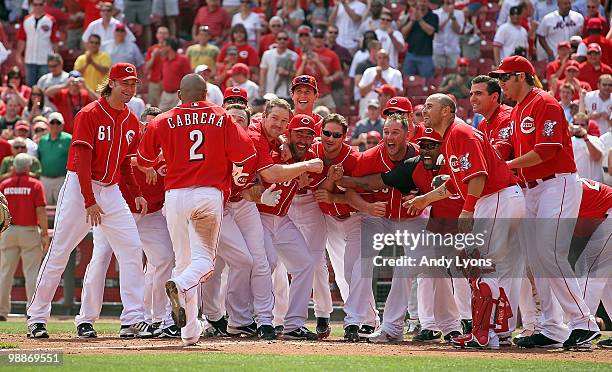 Orlando Cabrera of the Cincinnati Reds is greeted at home plate by teammates after hitting the game winning home run in the 10th inning against the...