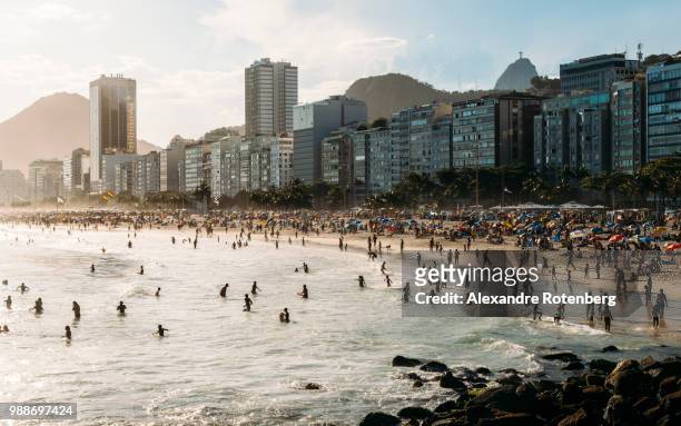 crowded copacabana beach with distant view of christ the redeemer statue far right, rio de janeiro, brazil, south america - rio de janeiro skyline stock pictures, royalty-free photos & images