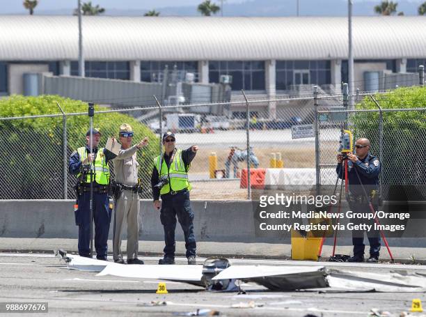 Investigators look over the scene of a small plane that crashed on the 405 freeway near John Wayne Airport in Irvine, California, on Friday, June 30,...