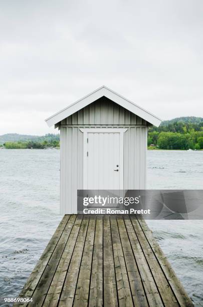 a hut at the end of a wooden lake pier. - roman pretot stock-fotos und bilder