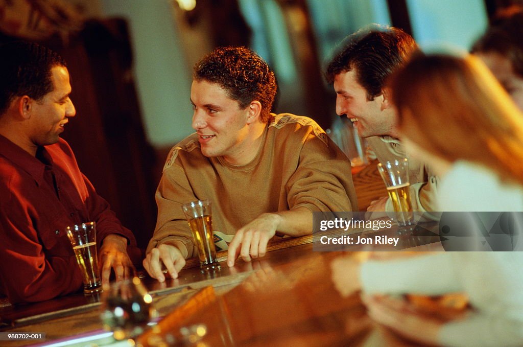 Three men talking and drinking in bar