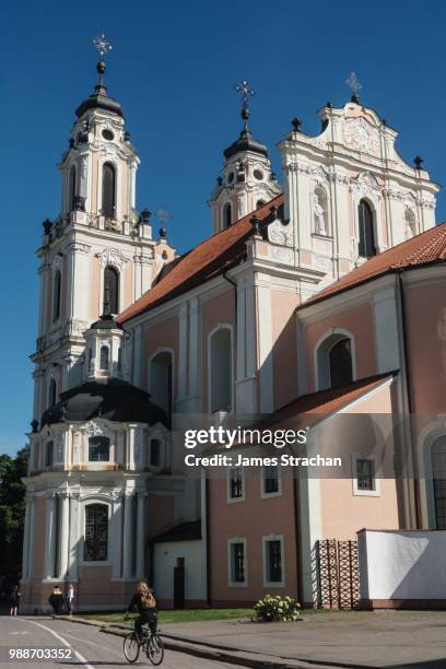 cyclist passes by strawberry and cream baroque church of st catherine, old town, unesco wolrd heritage site, vilnius, lithuania, europe - st catherine stock-fotos und bilder