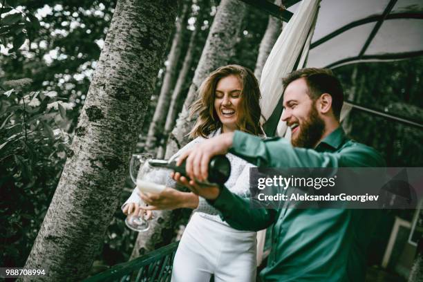 husband pouring champagne into glasses for him and his wife's anniversary - drunk husband stock pictures, royalty-free photos & images