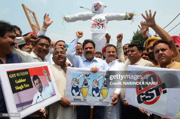 Activists of Congress Party shout slogans while holding an effigy depicting the Goods and Services Tax and Prime Minister Narendra Modi's government...