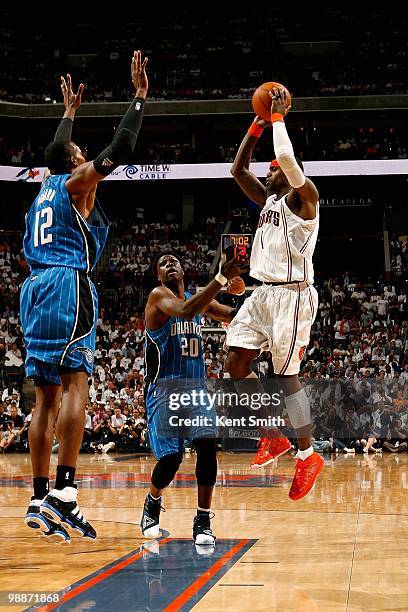 Stephen Jackson of the Charlotte Bobcats jumps up to pass over Dwight Howard and Mickael Pietrus of the Orlando Magic in Game Four of the Eastern...