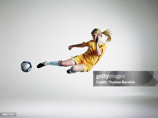 female soccer player kicking ball in mid air  - women soccer stock pictures, royalty-free photos & images