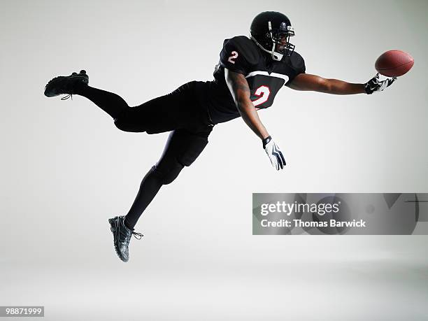 football player leaping in mid air to catch ball - profundo jugador de fútbol americano fotografías e imágenes de stock