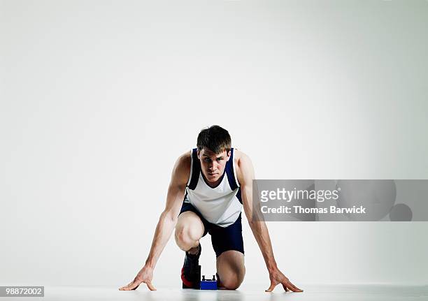 male runner in starting blocks looking up  - sprint photos et images de collection