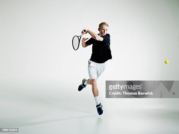 male tennis player in mid air returning ball - tennis photos et images de collection