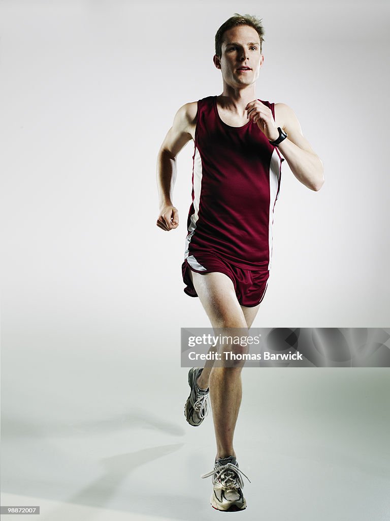 Male runner running mid stride on white background