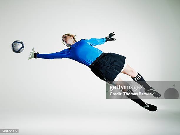 female goalie diving in mid air for soccer ball - goalie goalkeeper football soccer keeper stock pictures, royalty-free photos & images