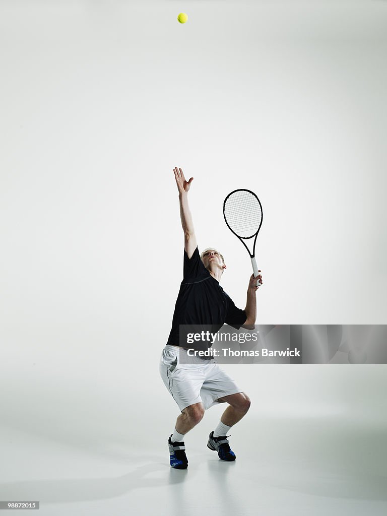 Male tennis player serving ball