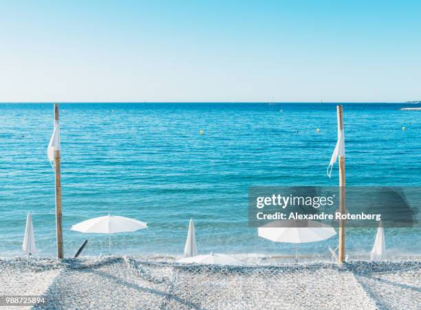 giant white beach umbrella next to the ocean against a blue sky in juan les pins, cote d'azur, provence, france, mediterranean, europe - juan les pins bildbanksfoton och bilder