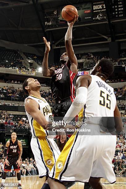 Joel Anthony of the Miami Heat puts a shot up against Danny Granger and Roy Hibbert of the Indiana Pacers during the game at Conseco Fieldhouse on...