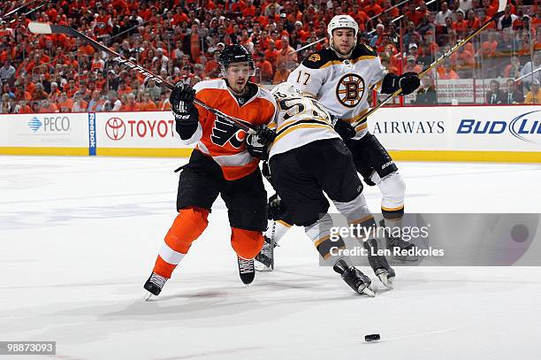 Danny Briere of the Philadelphia Flyers is played off the loose puck by Johnny Boychuk and Milan Lucic of the Boston Bruins in Game Three of the...