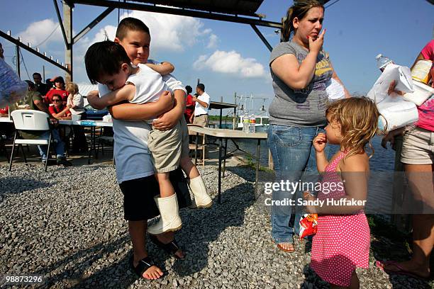 Jimmy Labat holds his brother Michael Labat while waiting in a line with unemployed commercial fishermen and their families for hand-outs from New...