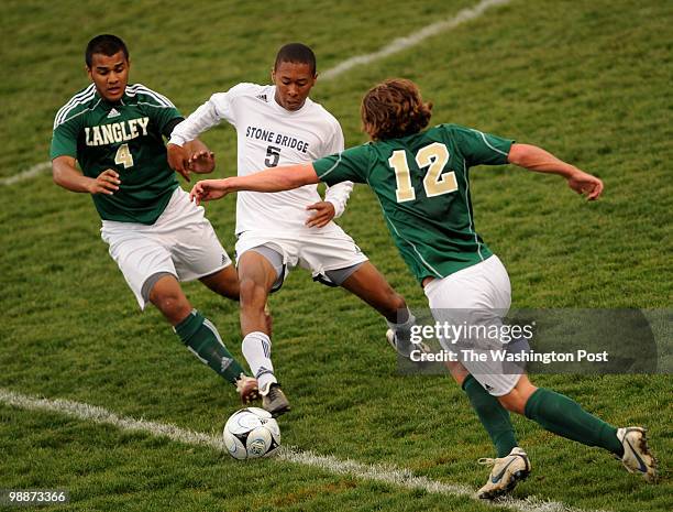 Stone Bridge's Mervyn Levy tries to feed the ball inbetween Langley defenders, Farhan Khan, left, and Alex Vorhees, right, during the game at Stone...