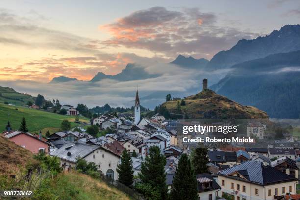 misty sky on the alpine village of ardez at sunrise, district of inn, lower engadine, canton of graubunden, switzerland, europe - graubunden canton stock-fotos und bilder