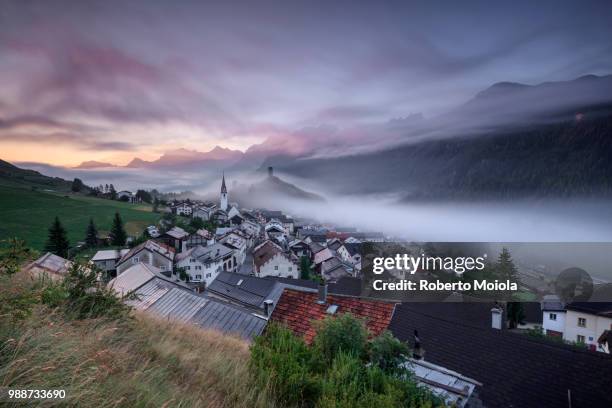 pink clouds and mist on the village of ardez at dawn, district of inn, lower engadine, canton of graubunden, switzerland, europe - graubunden canton stockfoto's en -beelden