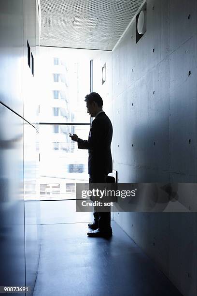 businessman using pda in passage - newbusiness stock pictures, royalty-free photos & images