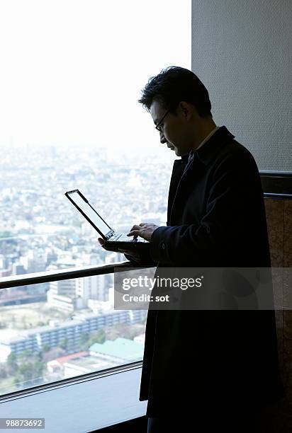 businessman using laptop by the window - newbusiness stock pictures, royalty-free photos & images