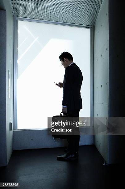 businessman using pda in entrance hall - vista trasera de tres cuartos fotografías e imágenes de stock