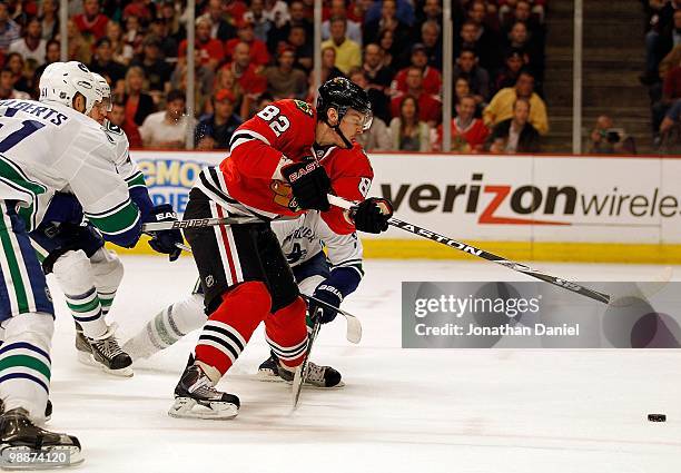 Tomas Kopecky of the Chicago Blackhawks pushes the puck up the ice under pressure from Andrew Alberts, Michael Grabner and Kevin Bieksa of the...