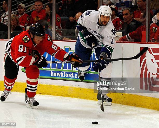 Andrew Alberts of the Vancouver Canucks passes the puck under pressure from Marian Hossa of the Chicago Blackhawks in Game Two of the Western...
