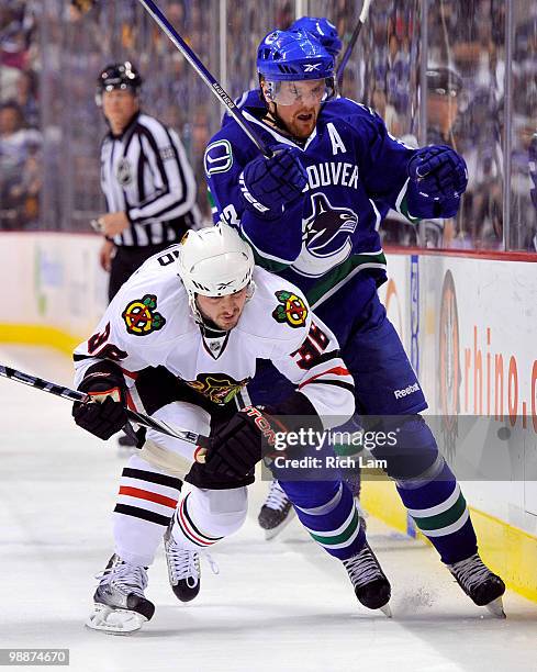 Henrik Sedin of the Vancouver Canucks is hit by Dave Bolland of the Chicago Blackhawks during the first period in Game Three of the Western...