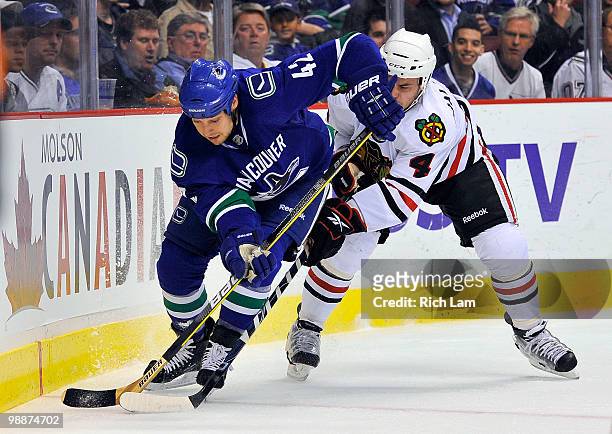 Kyle Wellwood of the Vancouver Canucks tries to break free from Niklas Hjalmarsson of the Chicago Blackhawks during the first period in Game Three of...