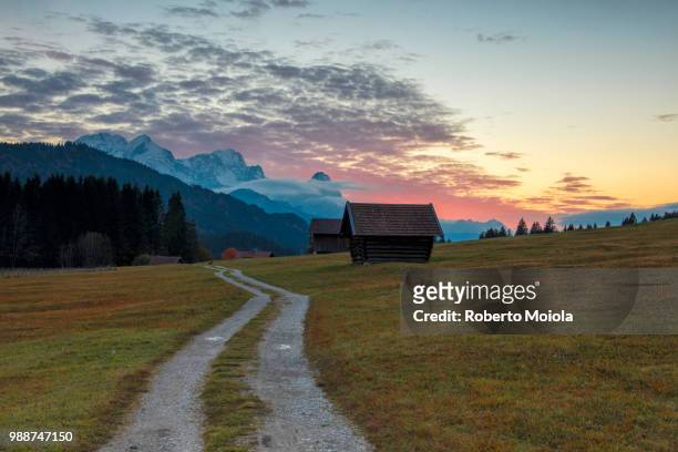 sunset on wooden huts and meadows with the alps in background, geroldsee, krun, garmisch partenkirchen, upper bavaria, germany, europe - krün ストックフォトと画像