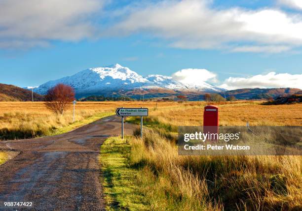 winter view of a red telephone box and road toward snow covered beinn resipol mountain in the moors of the scottish highlands, scotland, united kingdom, europe - peter snow stock pictures, royalty-free photos & images