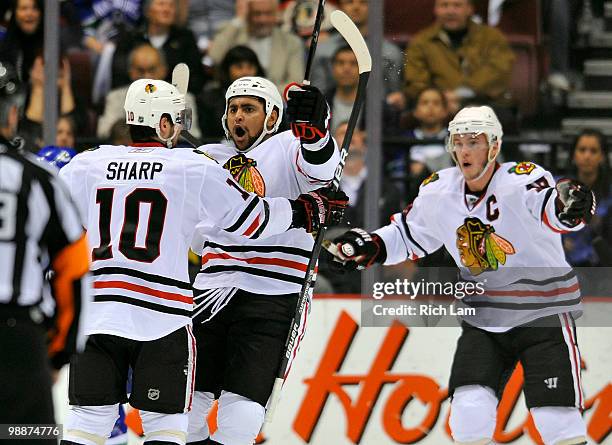 Dustin Byfuglien of the Chicago Blackhawks celebrates with Patrick Sharp and Jonathan Toews after scoring against the Vancouver Canucks during the...