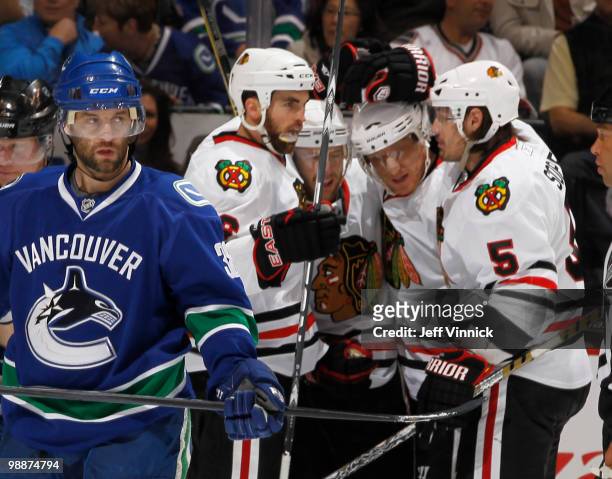 Pavol Demitra of the Vancouver Canucks skates away as Brent Sopel, Marian Hossa, Kris Versteeg and Andrew Ladd of the Chicago Blackhawks celebrate...