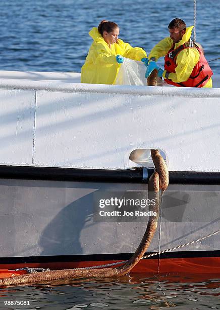 Workers on a shrimp boat pull an oil soaked absorption pad on board as they use it to collect the oil on the surface of the water from the massive...