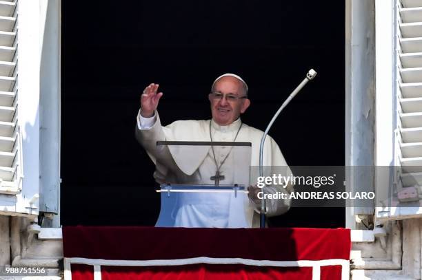 Pope Francis waves to the crowd from the window of the apostolic palace overlooking St Peter's square during the Sunday Angelus prayer, on July 1,...