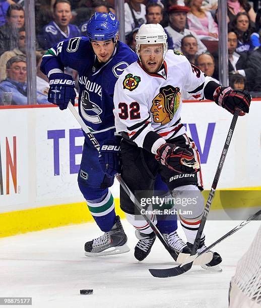 Shane O'Brien of the Vancouver Canucks tries to slow up Kris Versteeg of the Chicago Blackhawks while they battle for the loose puck during the...