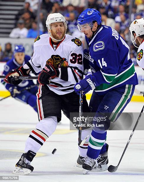 Kris Versteeg of the Chicago Blackhawks lays a hit on Alex Burrows of the Vancouver Canucks during the third period in Game Three of the Western...