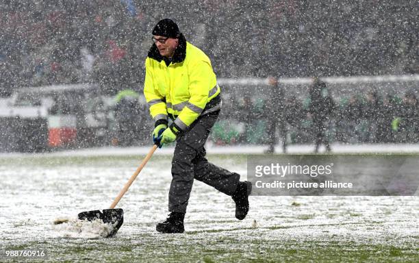 Helpers freeing the 16-meter line from snow during the German Bundesliga soccer match between Hannover 96 and 1899 Hoffenheim in the HDI Arena in...