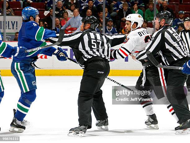 Linesmen Scott Driscoll and Jay Sharrers try to keep Kevin Bieksa of the Vancouver Canucks and Dustin Byfuglien of the Chicago Blackhawks apart in...