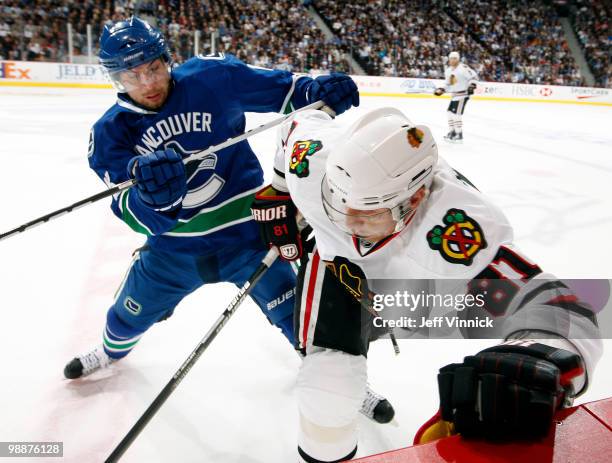 Steve Bernier of the Vancouver Canucks checks Marian Hossa of the Chicago Blackhawks into the boards in Game Three of the Western Conference...