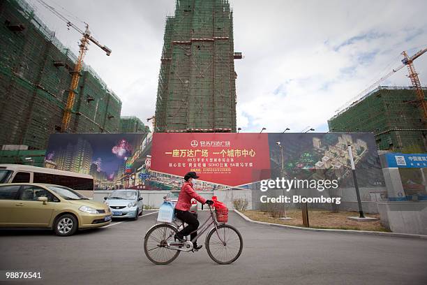 Woman rides her bicycle past a commercial development in Baotou, Inner Mongolia, China, on Wednesday, May 5, 2010. China's home prices may slump 30...