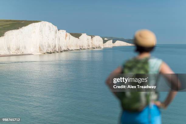 a woman looks towards the seven sisters while walking the south downs way, south downs national park, east sussex, england, united kingdom, europe - south downs national park stock pictures, royalty-free photos & images