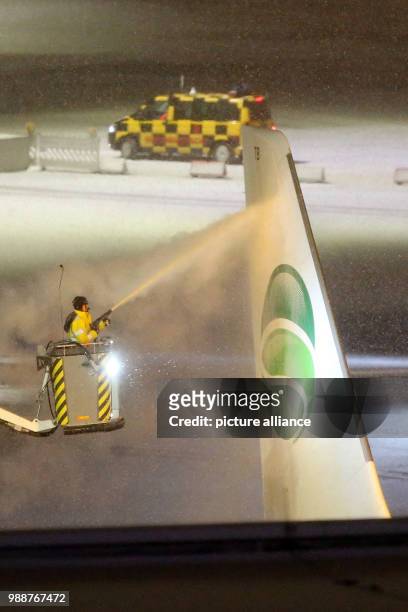 An airplane of the airline Germania is de-iced during the late evening at the airport in Hamburg, Germany, 10 December 2017. Photo: Bodo Marks/dpa
