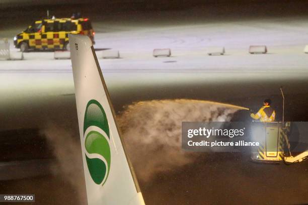 An airplane of the airline Germania is de-iced during the late evening at the airport in Hamburg, Germany, 10 December 2017. Photo: Bodo Marks/dpa