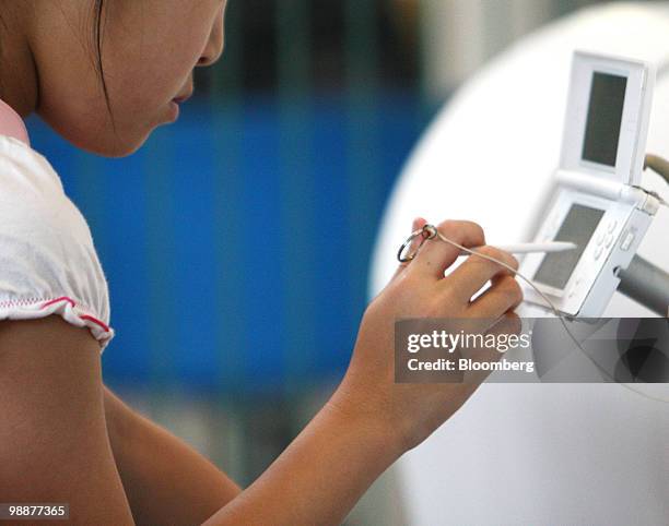 Girl tries out Nintendo Co.'s DS handheld game console at a showroom in Tokyo, Japan, on Thursday, May 6, 2010. Nintendo Co., the world's largest...