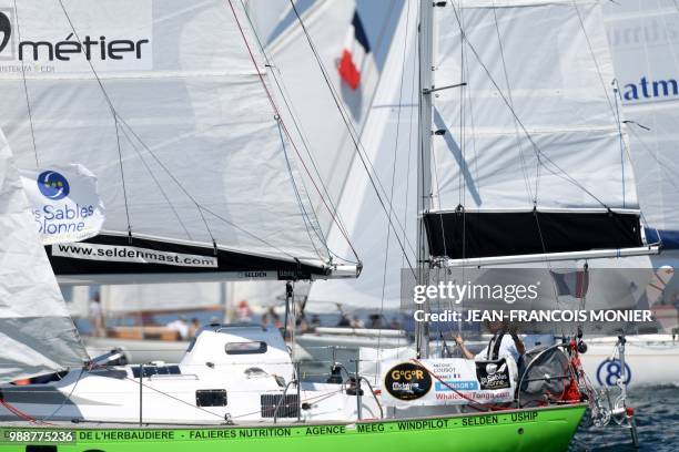 France's skipper Antoine Cousot on his boat "Metier Interim" competes from Les Sables d'Olonne Harbour on July 1 at the start of the solo...