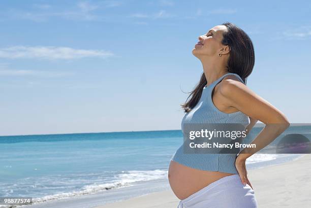 latin pregnant woman on the beach profile. - maternity wear stock-fotos und bilder