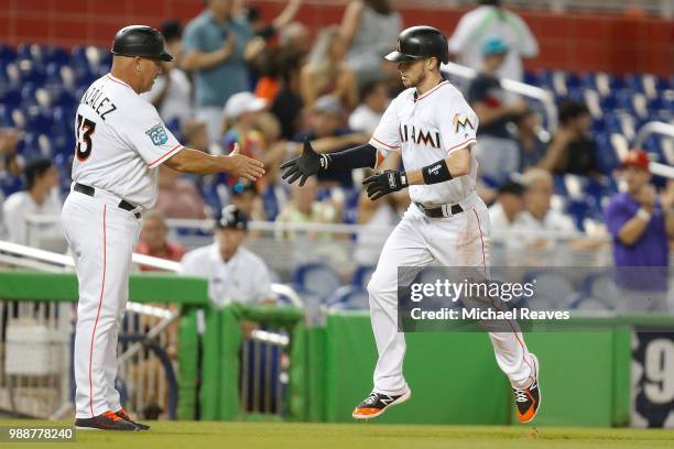 Riddle of the Miami Marlins high fives third base coach Fredi Gonzalez after hitting a solo home run in the fifth inning against the San Francisco...