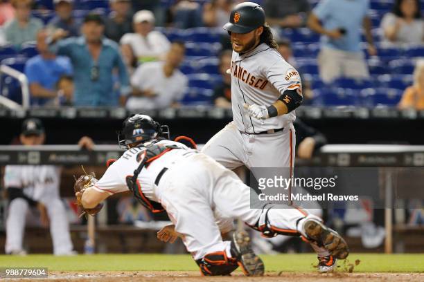 Bryan Holaday of the Miami Marlins dives to tag out Brandon Crawford of the San Francisco Giants in the eleventh inning at Marlins Park on June 14,...